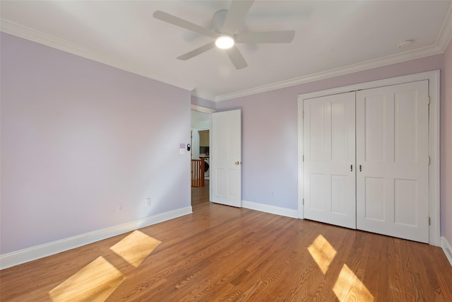 unfurnished bedroom featuring baseboards, wood finished floors, a closet, ceiling fan, and ornamental molding