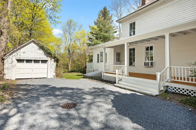 view of side of property featuring a porch, an outbuilding, cooling unit, a detached garage, and a chimney