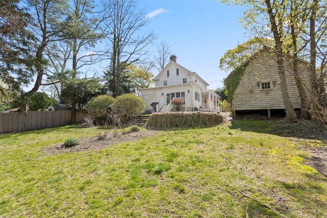 rear view of property featuring a lawn, a chimney, and fence