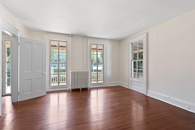 empty room featuring radiator, wood finished floors, and baseboards