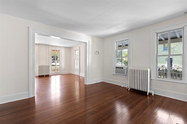 unfurnished room featuring baseboards, radiator heating unit, cooling unit, and wood-type flooring