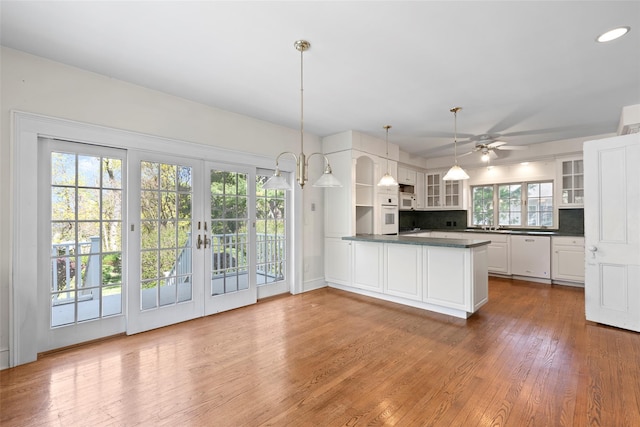 kitchen featuring white appliances, decorative backsplash, open shelves, dark countertops, and a peninsula