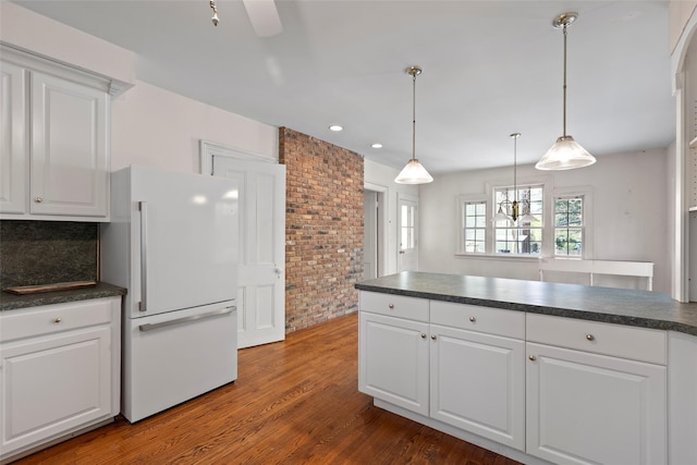 kitchen with freestanding refrigerator, decorative light fixtures, dark countertops, white cabinetry, and dark wood-type flooring
