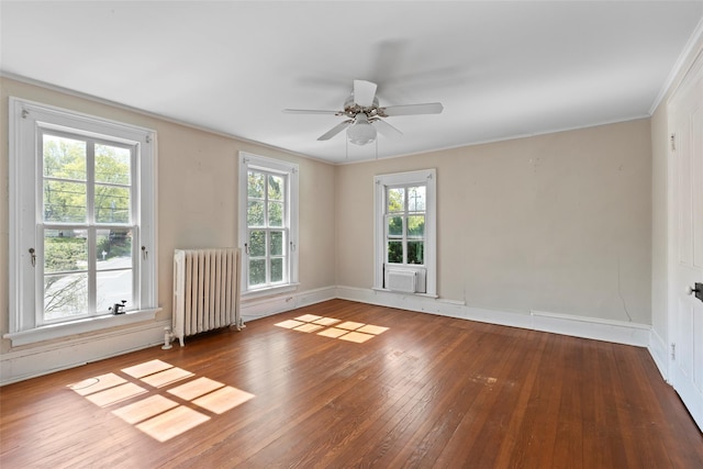 empty room featuring radiator heating unit, ornamental molding, wood-type flooring, baseboards, and a ceiling fan