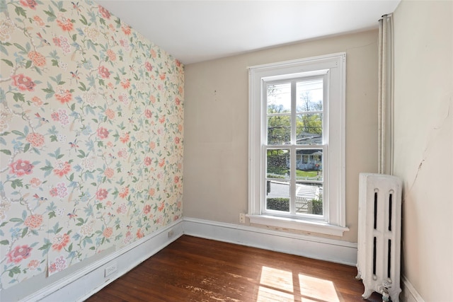 empty room featuring radiator, wallpapered walls, and plenty of natural light