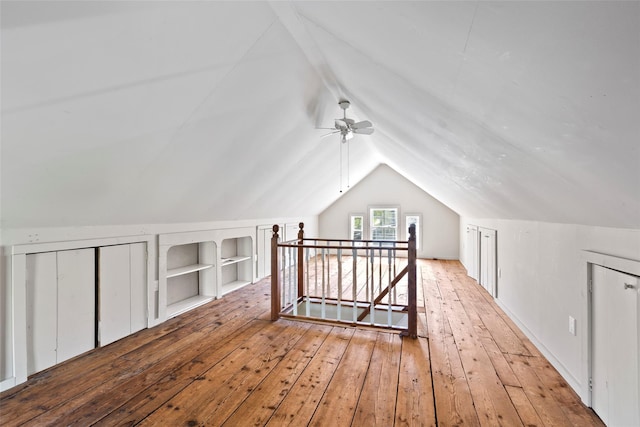 additional living space featuring ceiling fan, hardwood / wood-style flooring, built in features, and vaulted ceiling