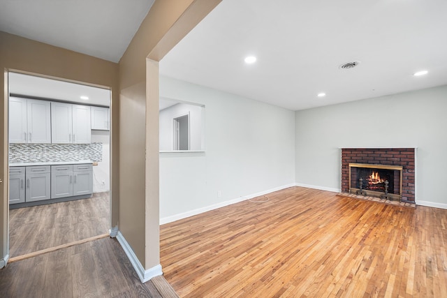 unfurnished living room featuring recessed lighting, visible vents, light wood-style flooring, and a fireplace