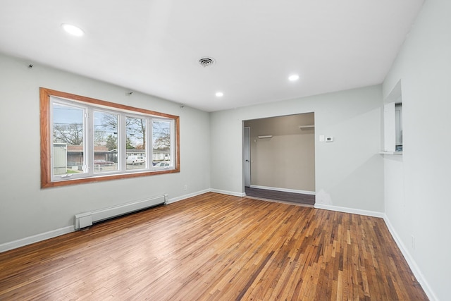 spare room with visible vents, baseboard heating, baseboards, recessed lighting, and wood finished floors