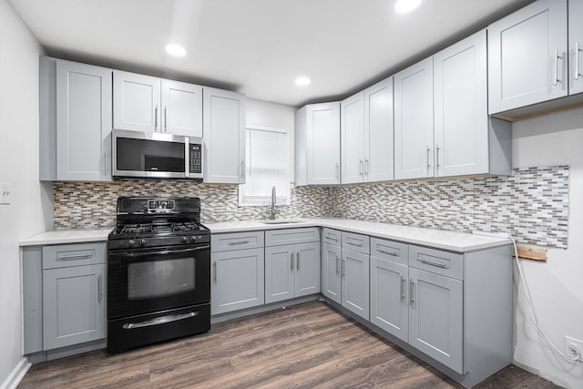 kitchen featuring gray cabinetry, black range with gas cooktop, light countertops, and stainless steel microwave