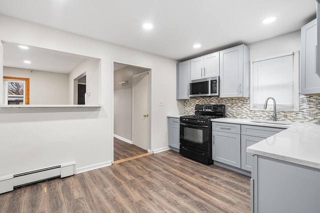 kitchen featuring stainless steel microwave, a sink, decorative backsplash, gas stove, and baseboard heating