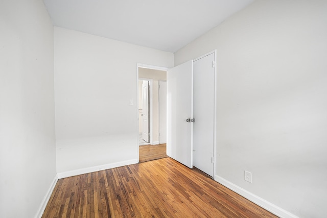 spare room with baseboards and wood finished floors