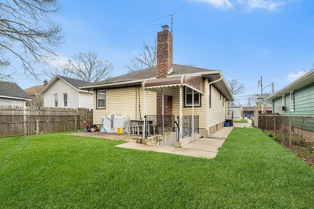 back of property featuring a chimney, a fenced backyard, and a lawn