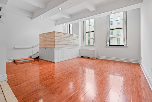 spare room featuring light wood-style flooring, beam ceiling, recessed lighting, a baseboard heating unit, and radiator