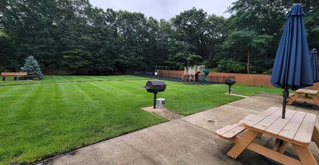 view of yard featuring a patio area, fence, and playground community