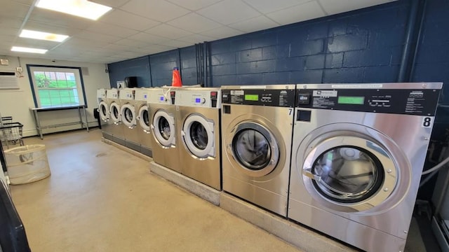 shared laundry area featuring washing machine and clothes dryer, concrete block wall, and a baseboard radiator