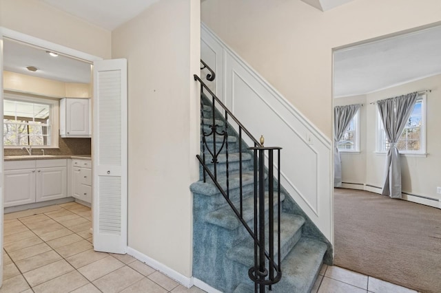 stairs with carpet, a healthy amount of sunlight, tile patterned flooring, and baseboards