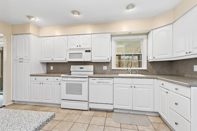 kitchen with white cabinets, white appliances, a sink, and tasteful backsplash