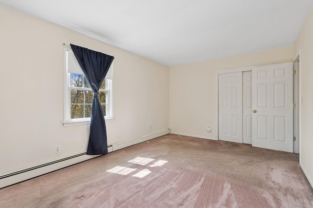 unfurnished bedroom with baseboards, a closet, carpet flooring, and baseboard heating