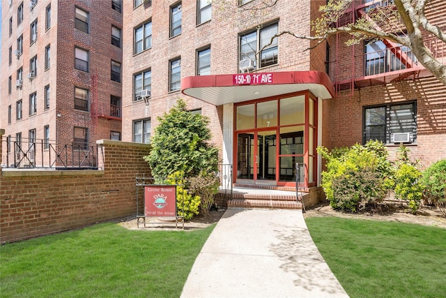 150-10 71st Ave Unit 5H, Kew Garden Hills, NY 11367 - view of exterior entry with brick siding, a yard, and cooling unit
