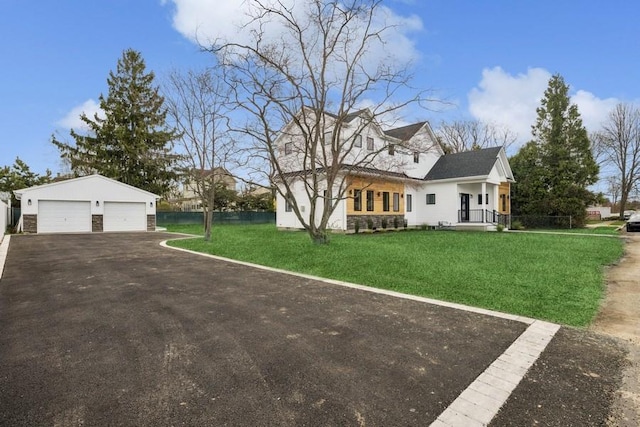view of front of property with a front lawn, stone siding, an outbuilding, and a detached garage