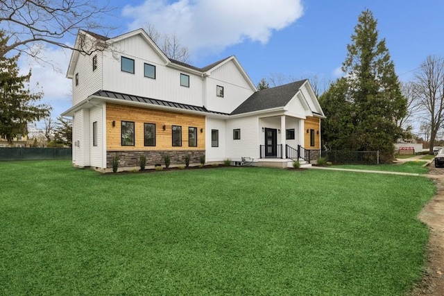 back of property with a standing seam roof, stone siding, and metal roof