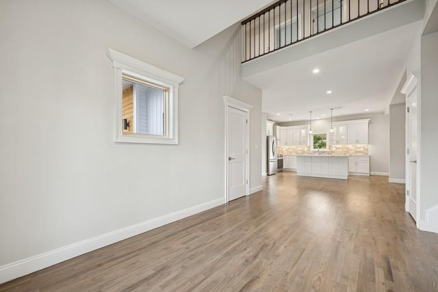 unfurnished living room with baseboards, light wood finished floors, and recessed lighting