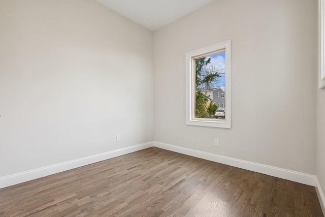 spare room with baseboards and wood finished floors