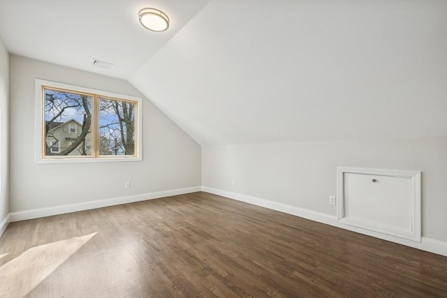 additional living space with wood finished floors, vaulted ceiling, and baseboards