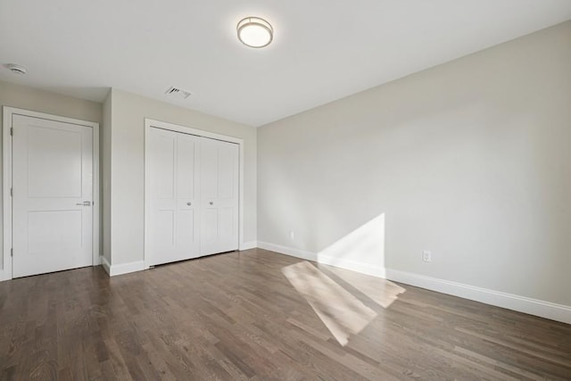 unfurnished bedroom featuring baseboards, dark wood-style flooring, and a closet