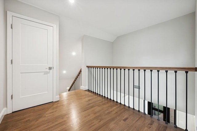 hall featuring an upstairs landing, wood finished floors, recessed lighting, and baseboards