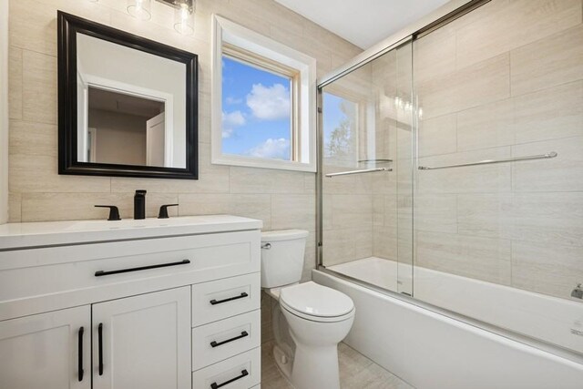 148 S 5th St, Lindenhurst, NY 11757 - bathroom with vanity, combined bath / shower with glass door, toilet, and tile walls