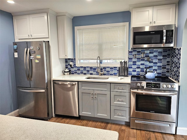 132-29 Brookville Blvd, Rosedale, NY 11422 - kitchen featuring appliances with stainless steel finishes, a sink, light countertops, wood finished floors, and white cabinetry