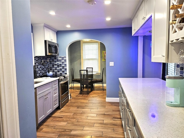 132-29 Brookville Blvd, Rosedale, NY 11422 - kitchen featuring stainless steel appliances, arched walkways, recessed lighting, decorative backsplash, and wood finished floors