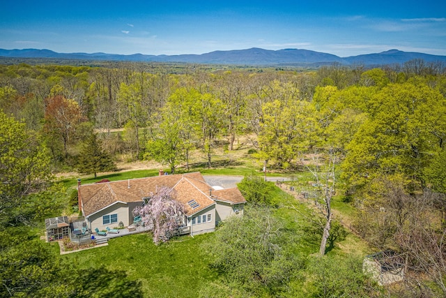 view from above of property with a heavily wooded area and a mountainous background