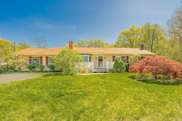 ranch-style house with a chimney, a front lawn, and a deck