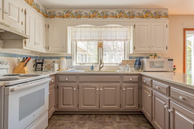 kitchen featuring white appliances, a sink, light countertops, and decorative backsplash