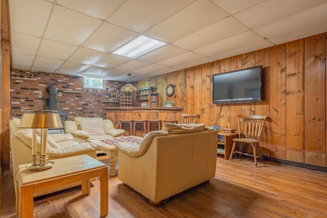 living area with a paneled ceiling, a wood stove, wood finished floors, and wood walls
