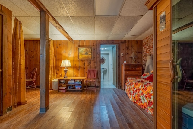 bedroom featuring wood walls, wood finished floors, and a drop ceiling
