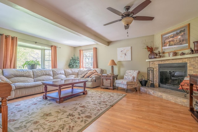 living room featuring a glass covered fireplace, ceiling fan, wood finished floors, and beamed ceiling