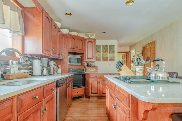 kitchen with stainless steel appliances, a sink, light wood-type flooring, decorative backsplash, and brown cabinets