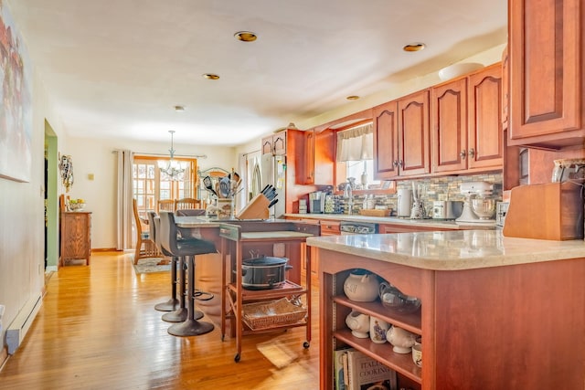 kitchen featuring baseboard heating, light wood-style flooring, freestanding refrigerator, backsplash, and open shelves