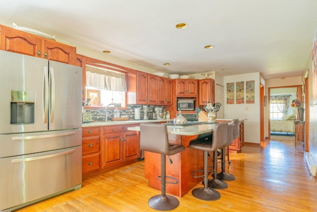 kitchen featuring appliances with stainless steel finishes, light countertops, backsplash, brown cabinets, and recessed lighting