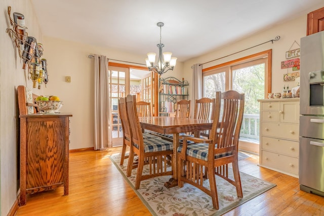 dining room featuring a chandelier, light wood-style floors, and baseboards