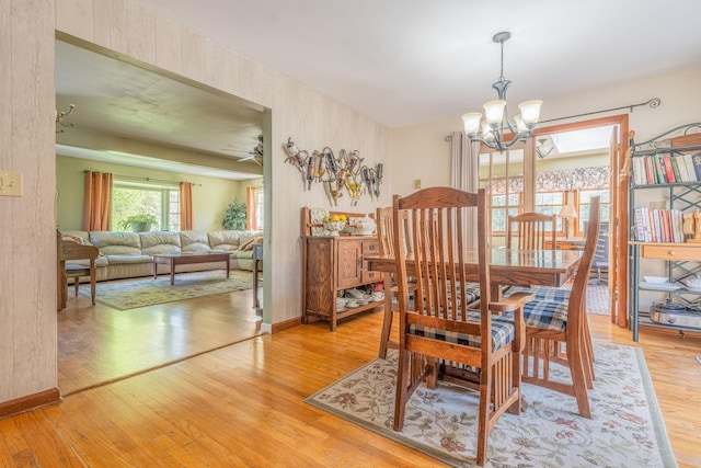 dining area with a chandelier, light wood finished floors, baseboards, and ceiling fan