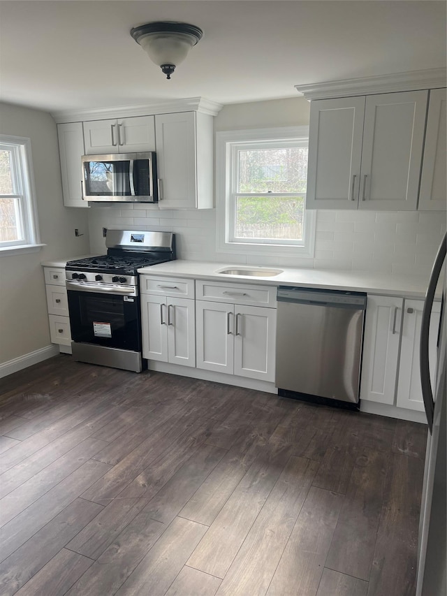 kitchen featuring light countertops, appliances with stainless steel finishes, dark wood-style floors, and decorative backsplash