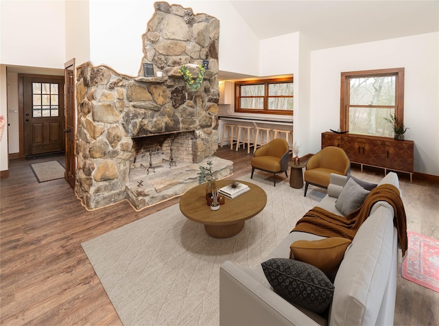 living area with high vaulted ceiling, baseboards, wood finished floors, and a fireplace