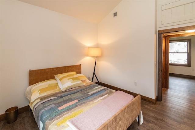 bedroom featuring baseboards, lofted ceiling, and wood finished floors