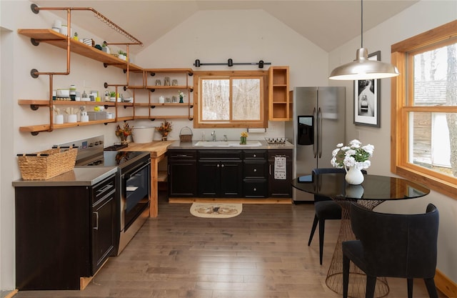 kitchen featuring stainless steel fridge with ice dispenser, range with electric cooktop, open shelves, and vaulted ceiling