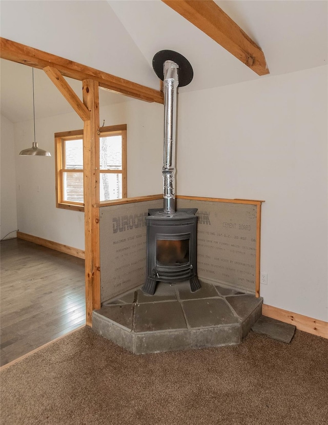 room details with wood finished floors, a wood stove, carpet flooring, and baseboards
