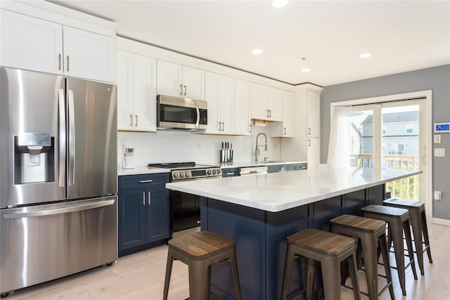 243 Sportsmans Ave, Freeport, NY 11520 - kitchen featuring light countertops, blue cabinets, a breakfast bar area, and stainless steel appliances